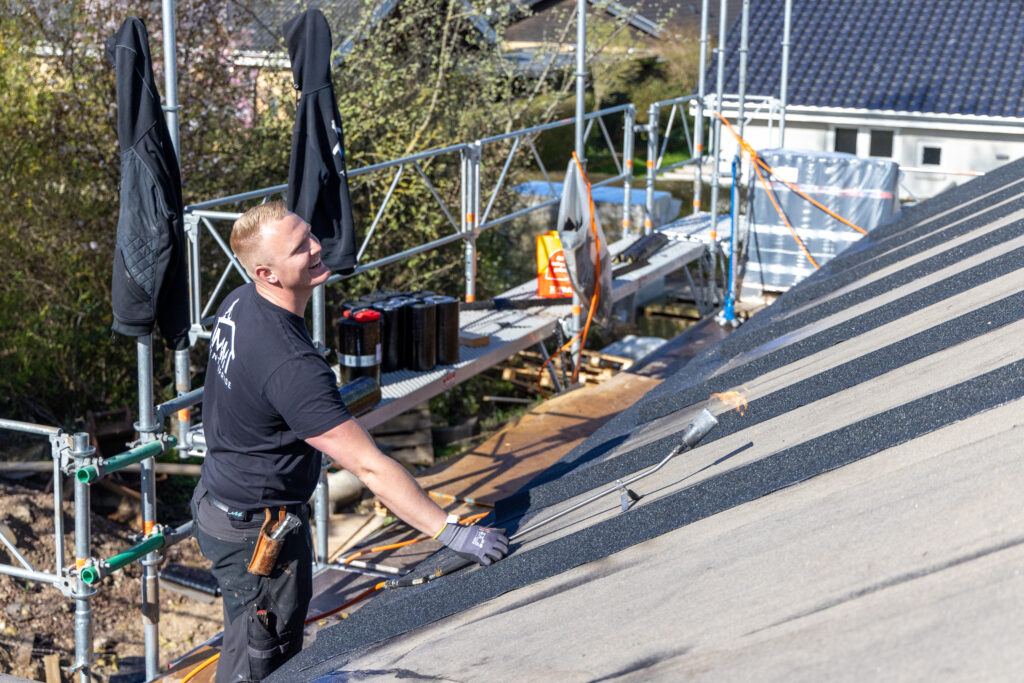 Tagdækker arbejder på nyt tag i solskin