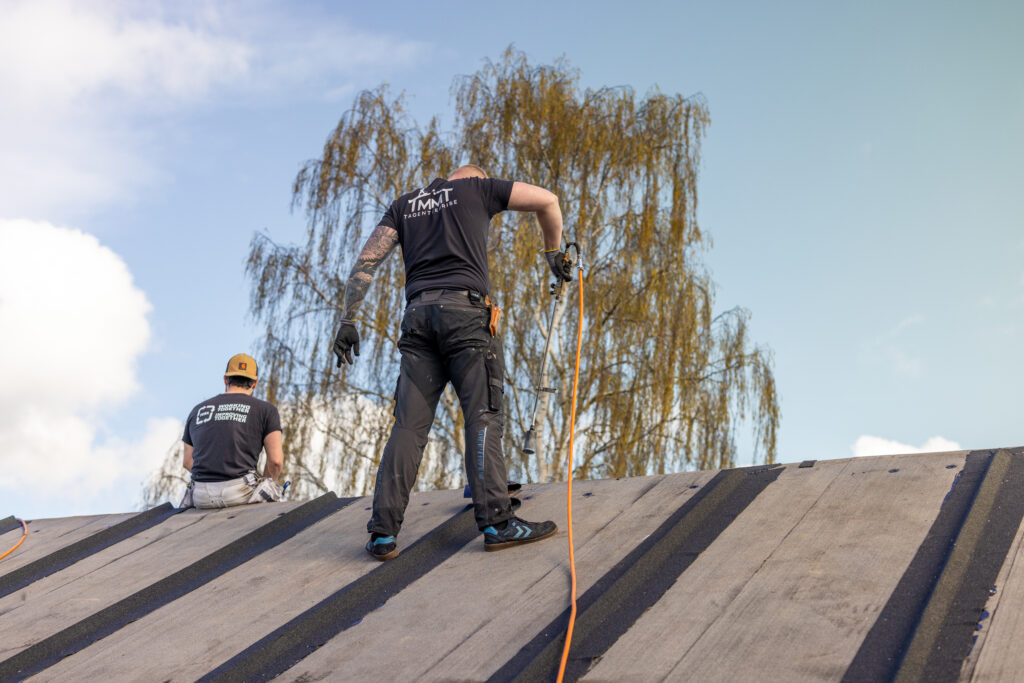 Tagarbejdere installerer nyt tag under klart himmel