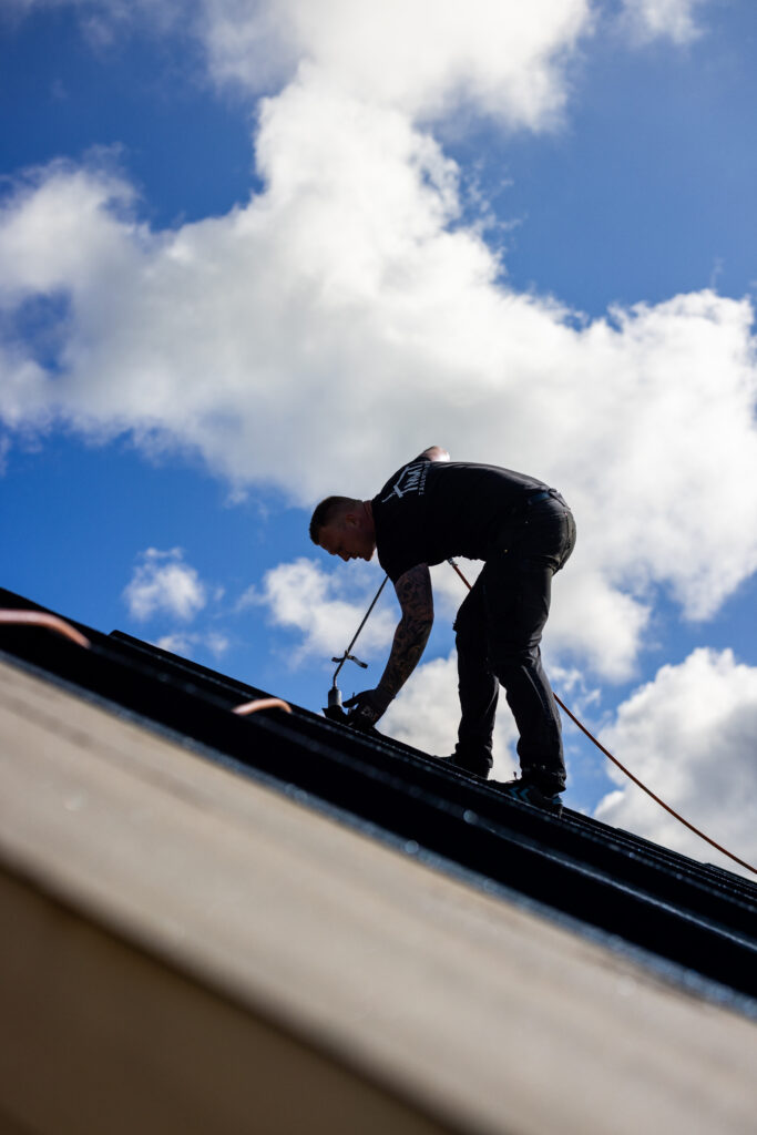 Tagdækker arbejder på tag under blå himmel