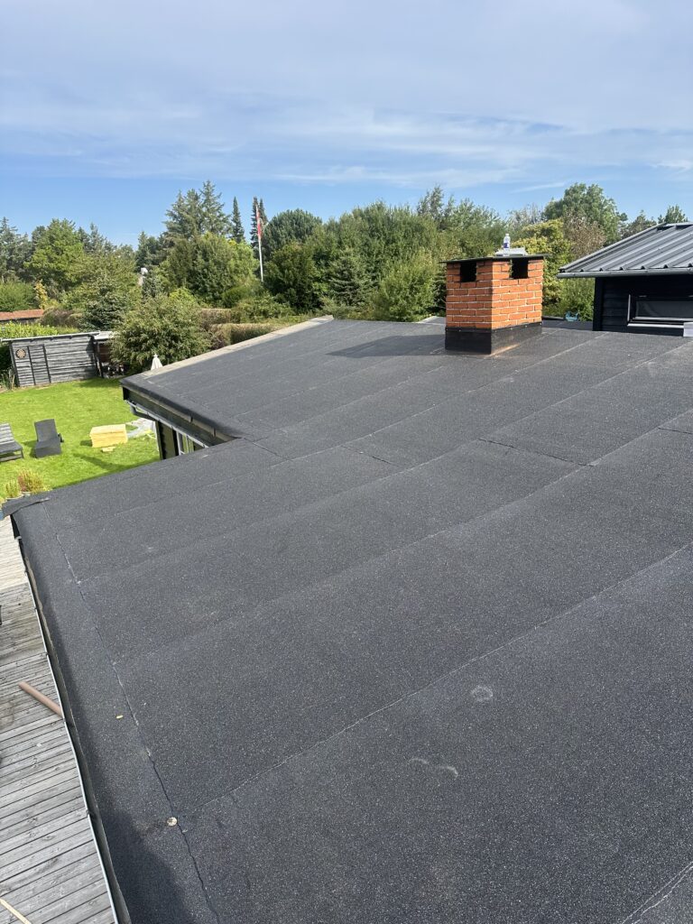 Fladt tag med sort tagpap og skorsten